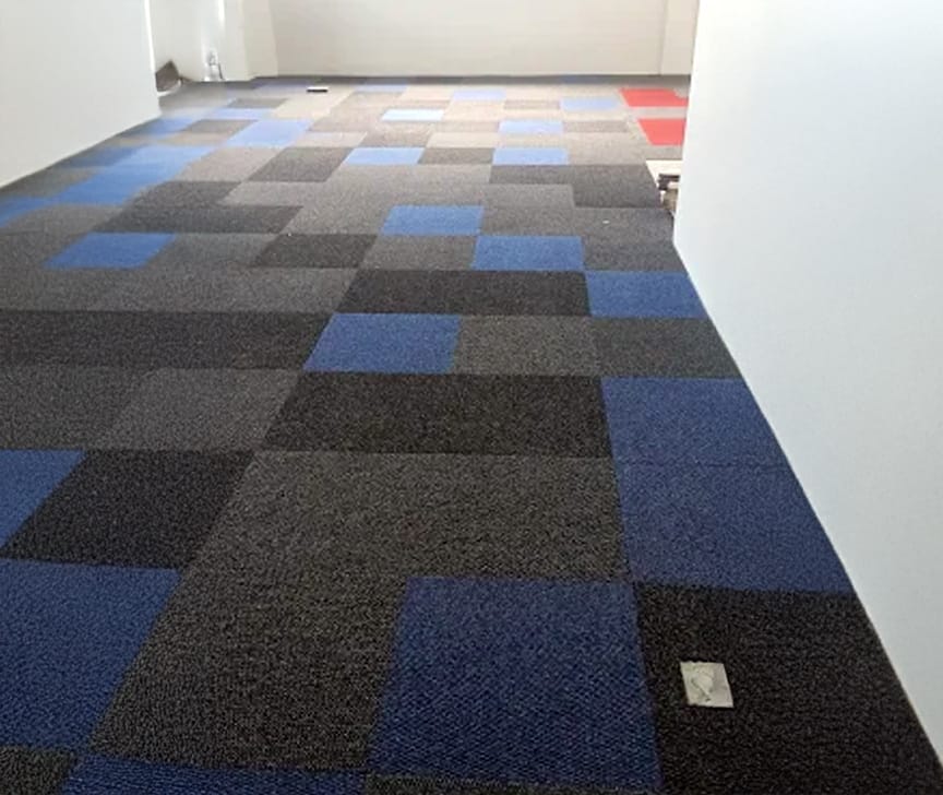 Carpete em placas modulares intercaladas em azul, cinza e grafite