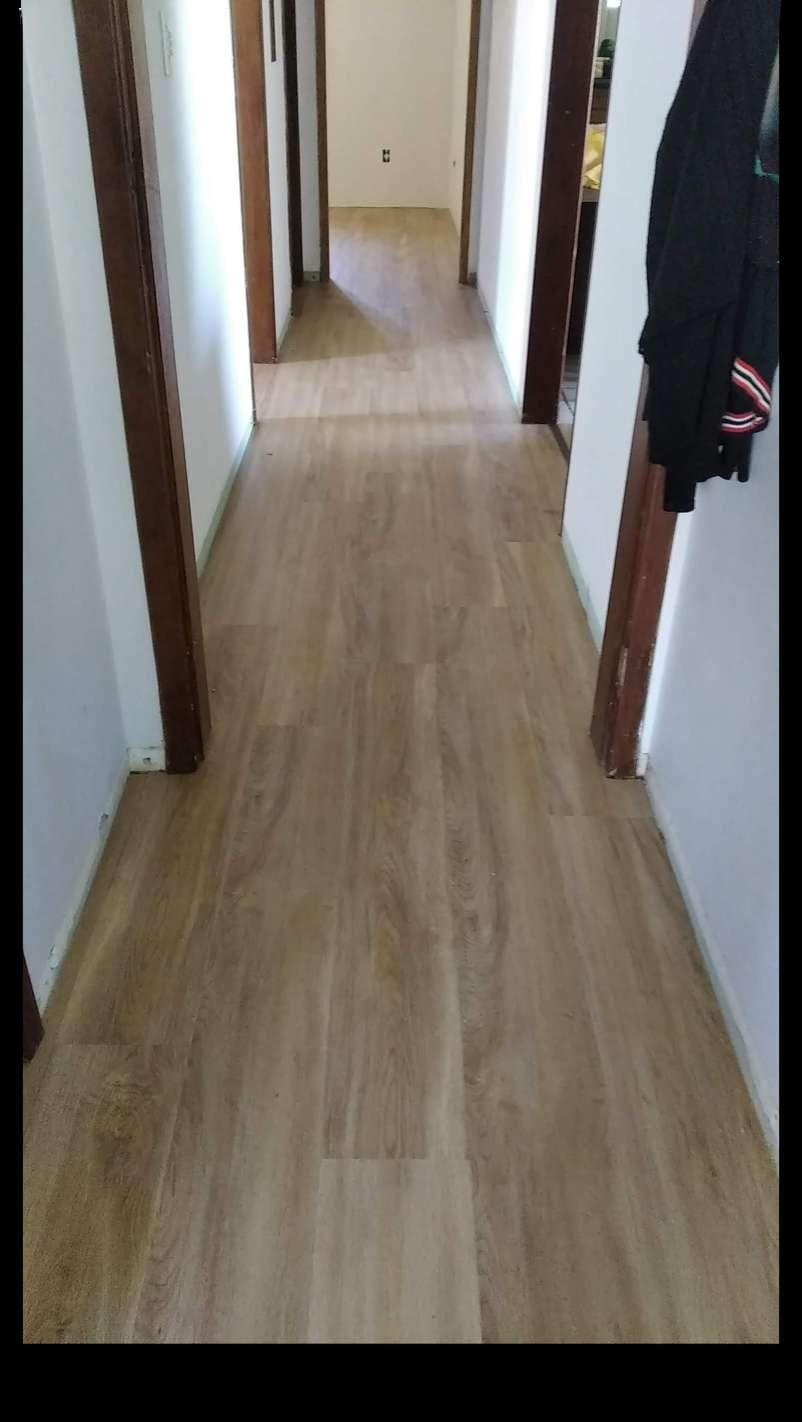 Corredor com piso vinílico claro e batentes de madeira escura nas portas