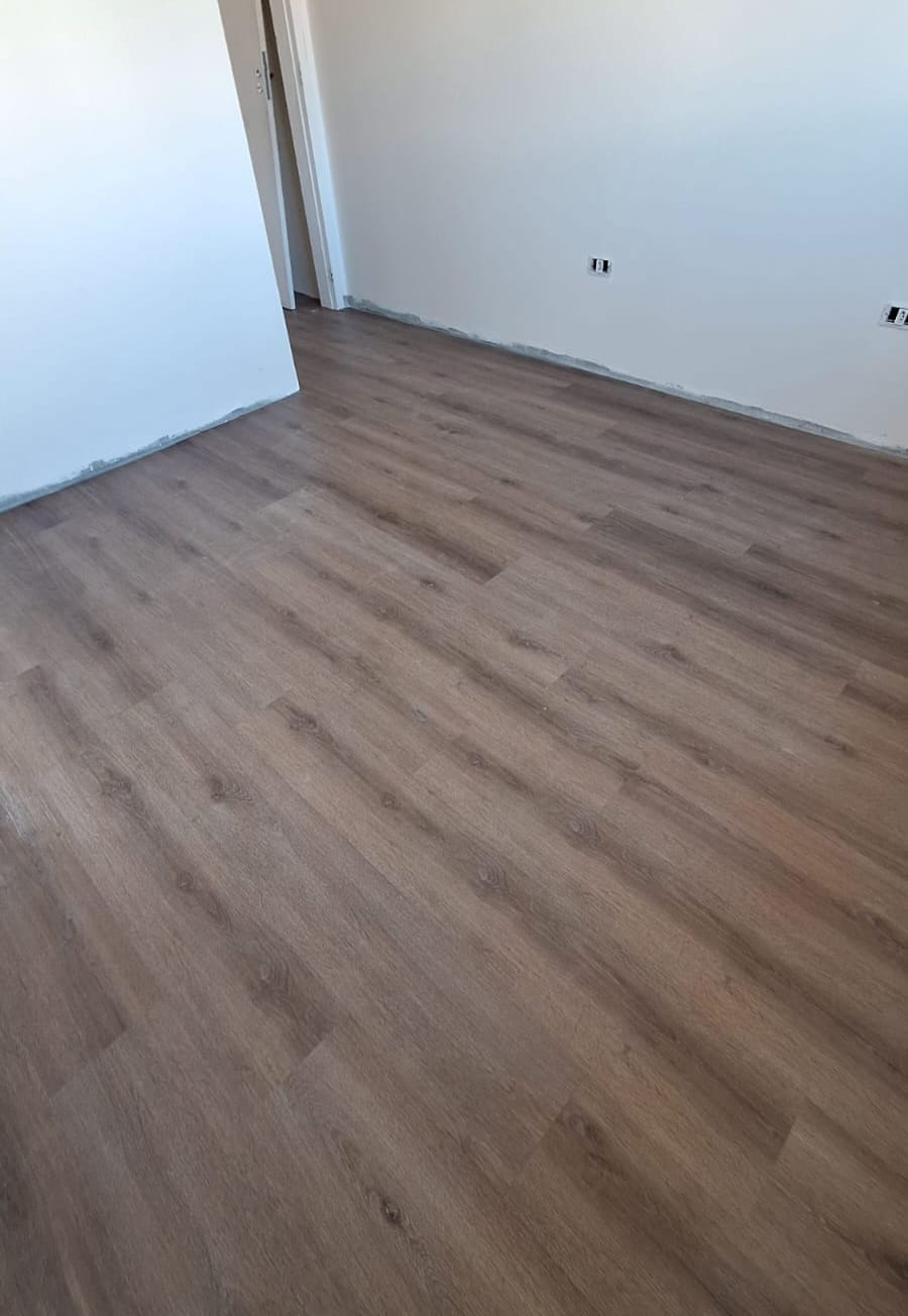Quarto vazio com piso vinílico em carvalho fumê e portas ao fundo
